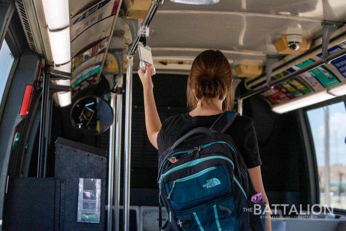 student holds rail in bus